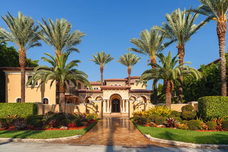Mediterranean style mansion with detailed landscaping, palm trees, and brick path. Mediterranean style mansion with detailed landscaping, palm trees, and brick path.