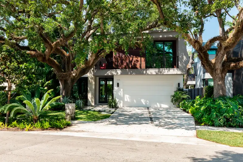 Modern home featuring lush tropical landscaping and professional tree care Modern home featuring lush tropical landscaping and professional tree care