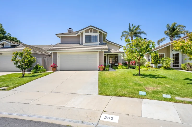 Freshly cut lawn and young trees in front of a suburban home.